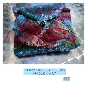 以下が含まれることがあります： 赤いリボンとボタン留めが付いた、小さくカラフルなキルティングバッグ。バッグはウール製で、パッチワークのデザイン。バッグの下に「Floating on Clouds Woolen Art」というテキストが印刷されています。「Gretes Traum」というテキストが右下の隅に印刷されています。