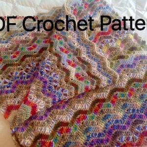 May include: A colorful crochet blanket with a chevron pattern. The blanket is made with a variety of colors, including brown, blue, green, red, and white. The blanket is folded in half and is lying on a white surface. The text "PDF Crochet Pattern" is written in black letters across the top of the blanket.