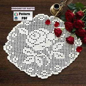 Può includere: Un centrino bianco all'uncinetto con bordo smerlato. Il centrino è posto su una superficie di legno scuro, con rose rosse e petali sparsi intorno. Il testo "CROCHET BY PATTY" e "Pattern PDF" sono visibili.