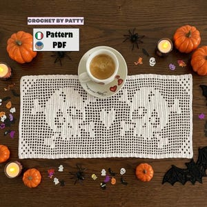 May include: A rectangular white crochet doily featuring a skull and heart pattern, displayed with a ceramic cup of coffee on a saucer. The image includes text reading CROCHET BY PATTY and Pattern PDF, surrounded by small orange pumpkins and confetti.