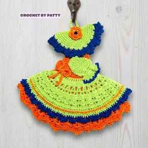 Può includere: Una presina all'uncinetto a forma di vestito realizzata con filato verde lime, arancione brillante e blu scuro. Il design presenta una gonna svasata, un corpetto con un fiore arancione e il testo CROCHET BY PATTY nell'angolo in alto a sinistra.