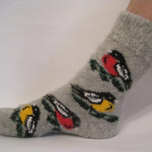 May include: Gray wool socks with a colorful bird pattern. The birds are red, yellow, and black with green leaves.