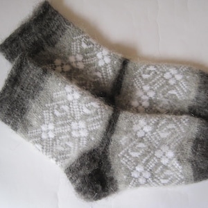 K&ouml;nnte beinhalten: Ein Paar flauschige wadenhohe Socken mit einem Farbverlauf von Anthrazit an den B&uuml;ndchen und Zehen bis hin zu einem helleren Grau in der Mitte. Die Socken sind durchgehend mit einem wei&szlig;en, geometrischen Rautenmuster verziert.