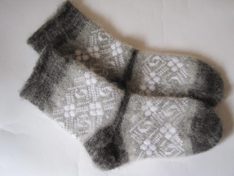 K&ouml;nnte beinhalten: Ein Paar flauschige wadenhohe Socken mit einem Farbverlauf von Anthrazit an den B&uuml;ndchen und Zehen bis hin zu einem helleren Grau in der Mitte. Die Socken sind durchgehend mit einem wei&szlig;en, geometrischen Rautenmuster verziert.