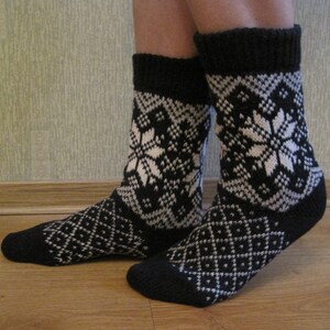 May include: A pair of black and white knitted socks with a snowflake pattern. The socks are made of a soft, warm material and are perfect for cold weather.