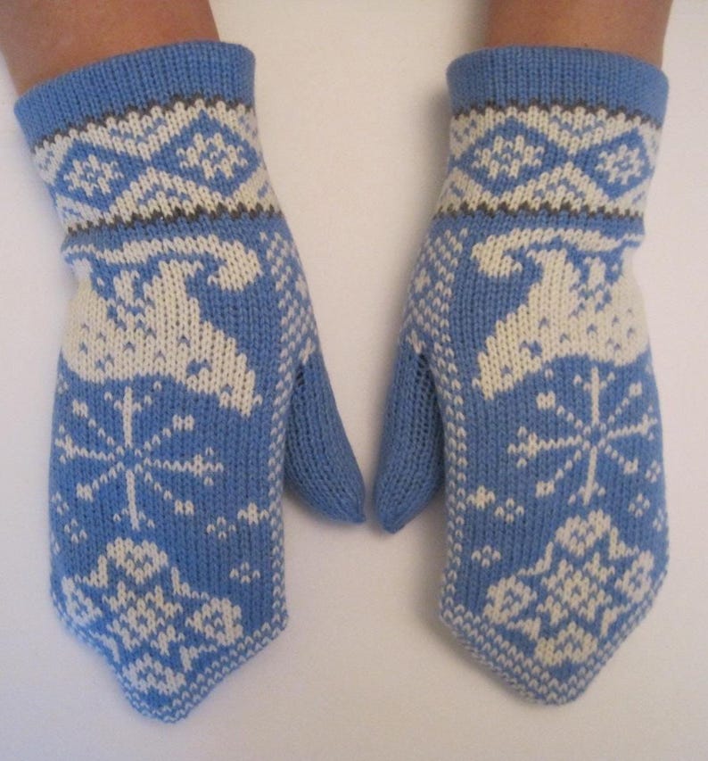 May include: A pair of light blue knitted mittens with white and dark grey geometric and snowflake patterns. The mittens have a thumb and are designed for warmth and winter wear.