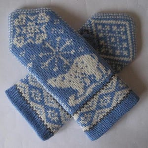 May include: A pair of light blue knitted mittens with white snowflake and animal patterns. The mittens have a cuff with a geometric design. The mittens are designed for cold weather and are made of a soft, warm material.