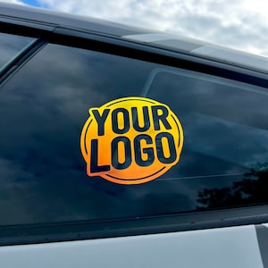 Puede incluir: Una pegatina circular amarilla y negra con el texto "YOUR LOGO" en la ventana de un coche.