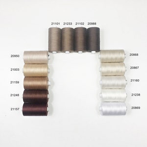 May include: A collection of spools of thread in various shades of brown, beige, and white. The spools are arranged in two columns, with the numbers 20950, 21003, 21159, 21248, 21157, 21101, 21233, 21102, 20988, 20868, 20867, 21160, 21238, and 20869 printed on the spools.