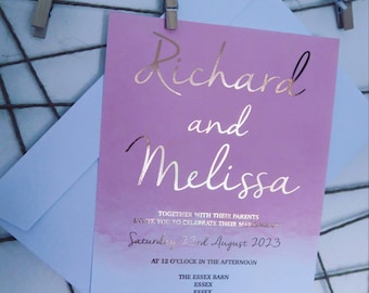 May include: A pink and blue wedding invitation with gold foil lettering. The invitation reads "Richard and Melissa" and includes the date "Saturday 23rd August 2023" and the location "The Essex Barn, Essex".
