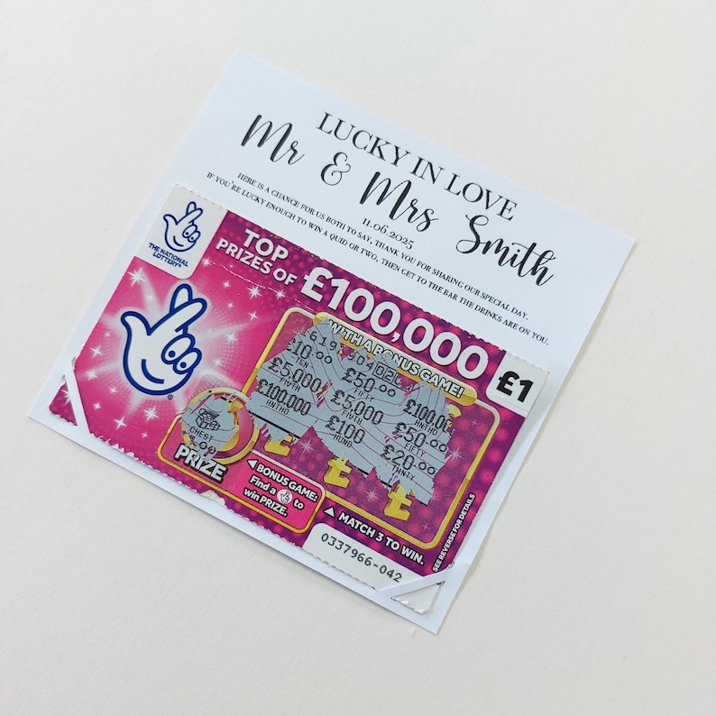 May include: A pink and silver lottery ticket with the text "Top Prizes of &pound;100,000 &pound;1" and "With a Bonus Game!" The ticket has a pink background with a white hand symbol and the text "The National Lottery".