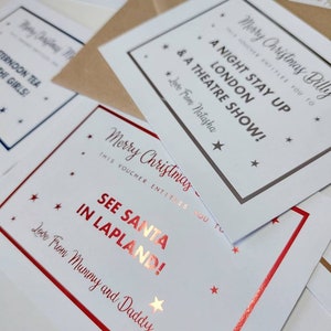May include: A set of Christmas gift vouchers with red and gold foil accents. The vouchers are printed with festive messages, including "See Santa in Lapland!" and "A Night Stay Up London & A Theatre Show!"