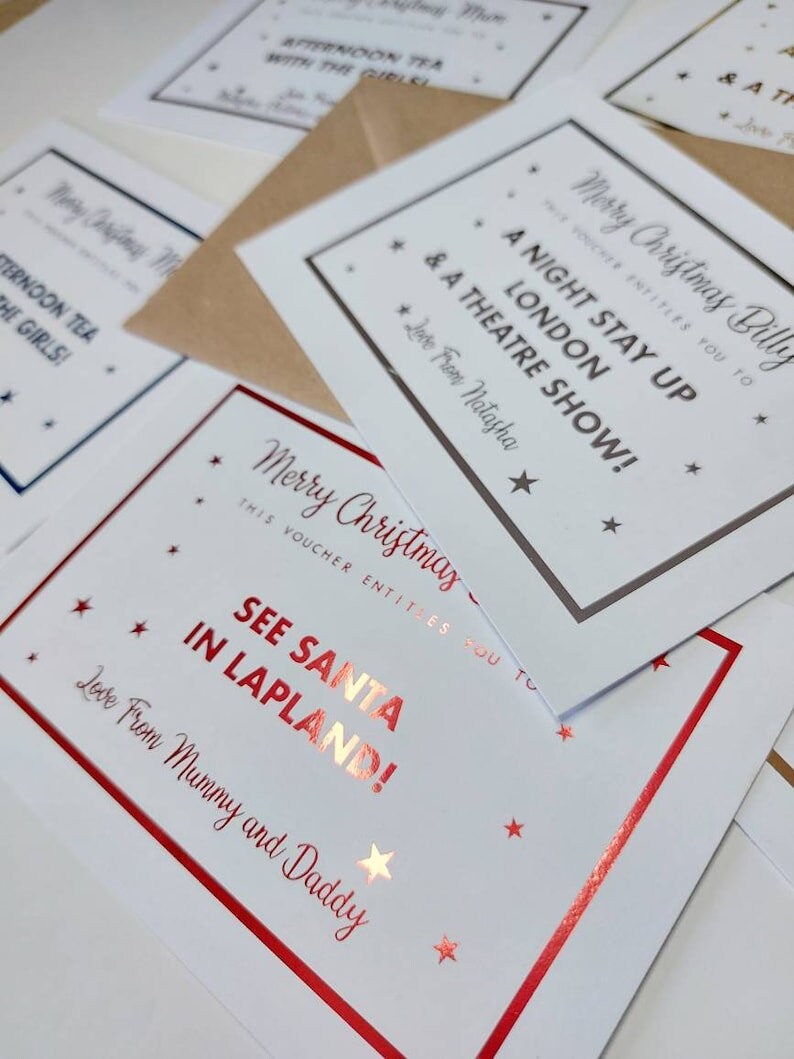 May include: A set of Christmas gift vouchers with red and gold foil accents. The vouchers are printed with festive messages, including "See Santa in Lapland!" and "A Night Stay Up London & A Theatre Show!"