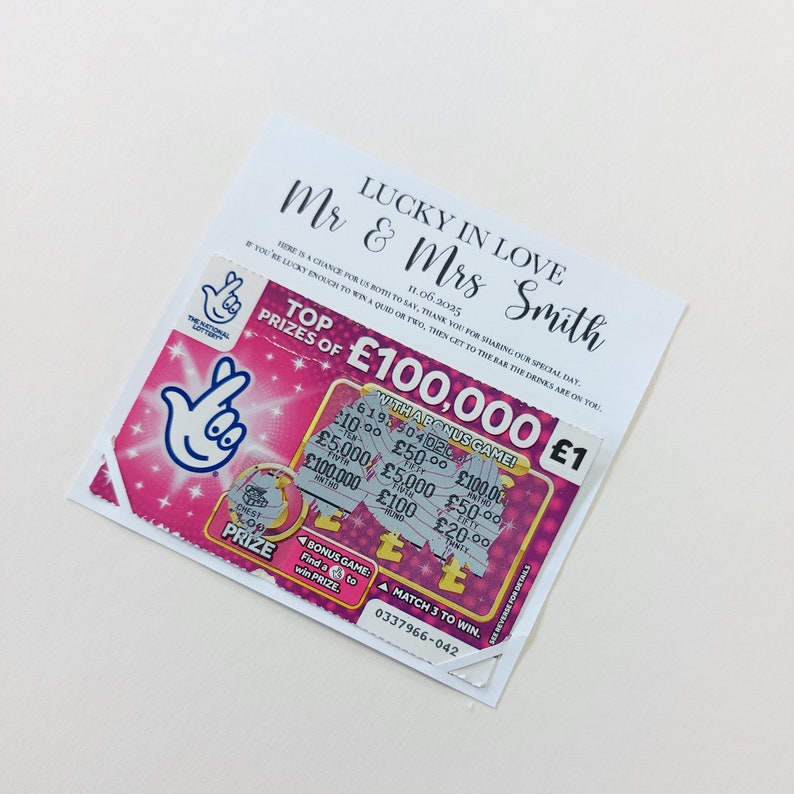 May include: A pink and white lottery ticket with the text "Top Prizes of &pound;100,000" and "With a Bonus Game!" The ticket has a pink hand with two fingers extended, and the text "Mr & Mrs Smith Lucky in Love 11.06.3025" is printed on a white card behind the ticket.