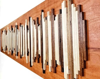 May include: A wooden wall art piece with a wave-like pattern made of various wood strips in shades of brown, beige, and white. The wood strips are arranged in a vertical pattern, creating a textured and dimensional effect.