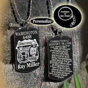 Könnte beinhalten: Schwarzer Erkennungsmarken-Anhänger mit einer silbernen Kette. Auf der Vorderseite steht: "WASHINGTON 6488 CORRECTIONAL OFFICER Ray Miller." Die Rückseite enthält ein Gebet. Option Halskette oder Schlüsselanhänger.