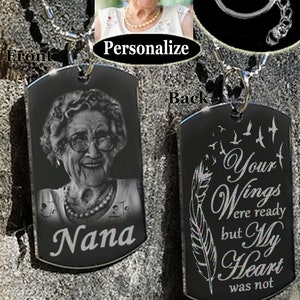 May include: A black metal dog tag necklace or keychain with a personalized photo of a woman on the front and the text "Your Wings were ready but My Heart was not" on the back.