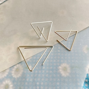 May include: Three silver triangle shaped earrings. The earrings are made of thin wire and are designed to be worn as a pair.