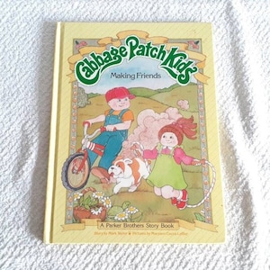 Op de afbeelding: Een gele boekomslag met een groene illustratie van Cabbage Patch Kids-personages. De titel van het boek is "Cabbage Patch Kids Making Friends" en het is een Parker Brothers Story Book.