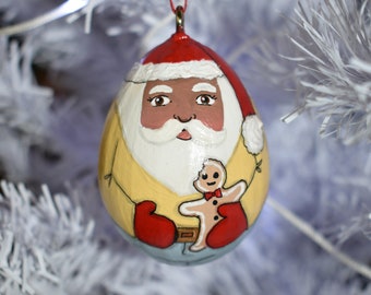 Black Santa wearing yellow shirt, blue jeans, red Santa hat eating gingerbread cookie