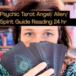 Op de afbeelding: Een persoon houdt een tarotkaartspel met een turquoise en wit ontwerp vast. De tekst op de afbeelding luidt "Psychic Tarot Angel/ Alien/ Spirit Guide Reading 24 hr". De achtergrond is wazig.