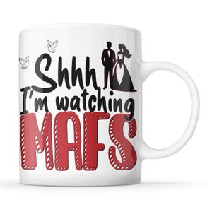 May include: White ceramic coffee mug with a black and red design. The mug features the text "Shhh, I'm watching MAFS" with a stylised bride and groom graphic.