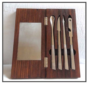 Peut inclure: Une bo&icirc;te en bois avec un couvercle &agrave; charni&egrave;res, contenant cinq outils en argent. La bo&icirc;te est en bois fonc&eacute; avec un motif de grain. Les outils sont dispos&eacute;s en rang&eacute;e, les poign&eacute;es vers le haut. Les outils sont de formes et de tailles diff&eacute;rentes, et ils semblent &ecirc;tre en m&eacute;tal.