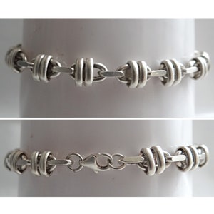 May include: A silver chain bracelet with a clasp closure. The chain is made of interlocking oval links.
