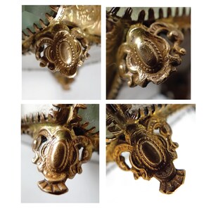 Op de afbeelding: Close-up van vier sierlijke, goudkleurige metalen poten met ingewikkelde details. Elke poot heeft een centrale ovale vorm met een verhoogde rand en een decoratief ontwerp.