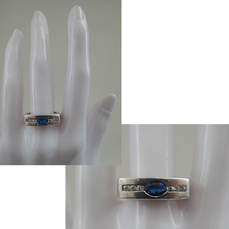 Op de afbeelding: Een zilveren ring met een blauwe ovale edelsteen en kleinere heldere edelstenen gezet in een band.