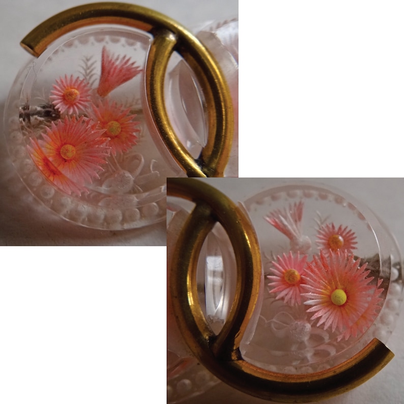 May include: Two clear glass buttons with gold metal frames. The buttons feature a floral design with pink and yellow flowers.