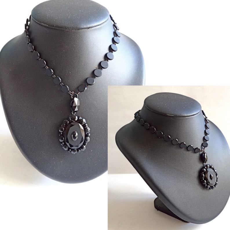 May include: Two black necklaces with a pendant made of black glass beads. The necklaces are displayed on black mannequins.