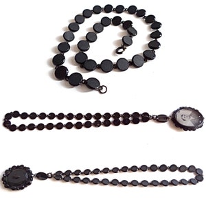 May include: Three black beaded necklaces, one with a locket featuring a black and white photo, and another with a large black button.