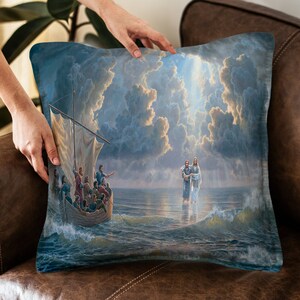May include: A throw pillow with a painting of Jesus walking on water. The painting depicts Jesus walking on the water with a man in a boat behind him. The sky is cloudy and there is a bright light shining down from the clouds.