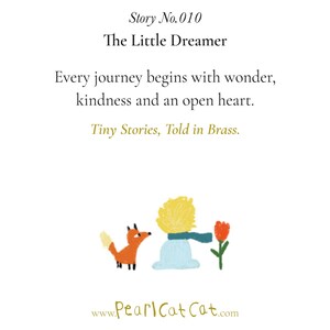 May include: A white card featuring the text Story No. 010 The Little Dreamer, Every journey begins with wonder, kindness and an open heart, Tiny Stories, Told in Brass. Below is a colourful illustration of a fox, a person, and a red flower.