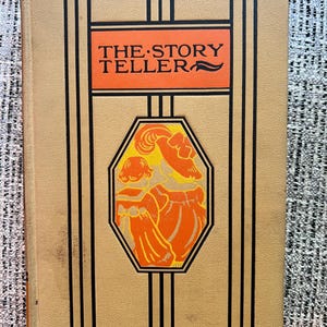 May include: A vintage book titled "The Story Teller" with a yellow cover and black and orange accents. The cover features an illustration of two women in orange dresses.