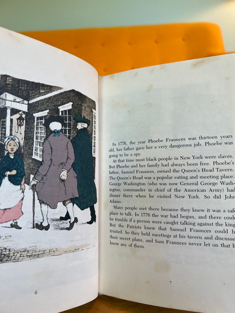 K&ouml;nnte beinhalten: Eine Illustration einer Taverne mit drei Personen, die vor dem Geb&auml;ude stehen. Die Taverne hei&szlig;t "The Queen's Head Tavern". Der Text im Bild lautet: "Im Jahr 1776, als Phoebe Fraunces dreizehn Jahre alt war, gab ihr ihr Vater einen sehr gef&auml;hrlichen Job. Phoebe sollte eine Spionin werden."
