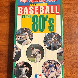 May include: A VHS video cassette with a green, yellow, and white cover featuring the text "The Sporting News Presents Baseball in the 80's". The cover features a collage of baseball players in action.