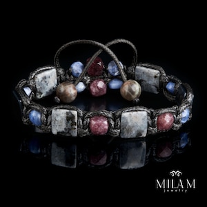 May include: A black braided bracelet with grey, blue, and pink gemstone beads. The bracelet is tied with a knot and has a tassel.