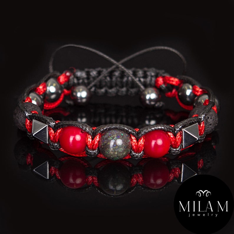 May include: A black braided bracelet with red and gray beads, black lava rock beads, and silver pyramid-shaped accents.