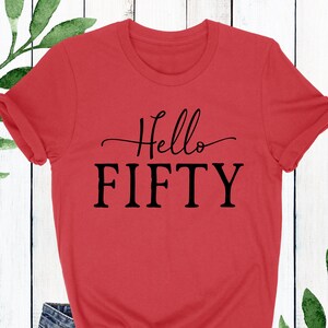 May include: Red t-shirt with black text that says "Hello Fifty".