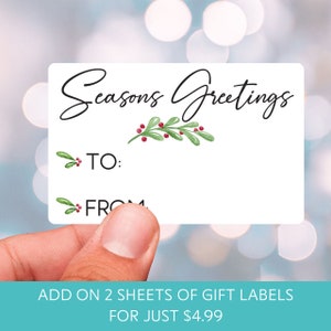 a hand holding a card that says seasons greetings to from