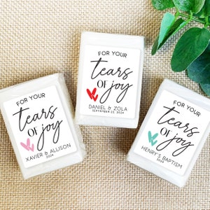 May include: Three white soap bars with labels that say "For Your Tears of Joy" with different colored hearts and names and dates.