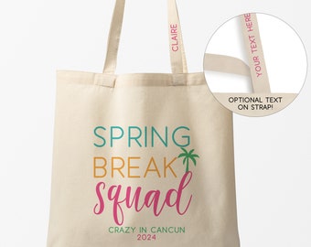 May include: A beige canvas tote bag with the text "SPRING BREAK Squad" in colorful letters. The text "CRAZY IN CANCUN 2024" is printed below the main text. The bag has two straps with the names "CLAIRE" and "YOUR TEXT HERE" printed on them.