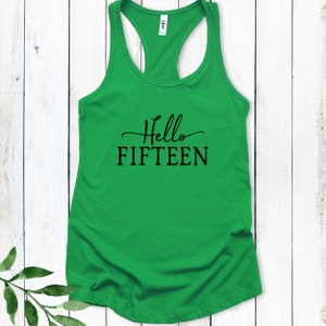 May include: Green tank top with the text "Hello Fifteen" in black lettering.