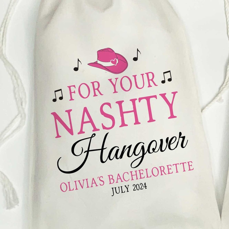 Puede incluir: Una bolsa de tela blanca con cord&oacute;n que presenta un gr&aacute;fico de sombrero de vaquero rosa con notas musicales. El texto dice: FOR YOUR NASHTY Hangover OLIVIA'S BACHELORETTE JULY 2024. El dise&ntilde;o combina letras rosas en bloque y fuente negra.