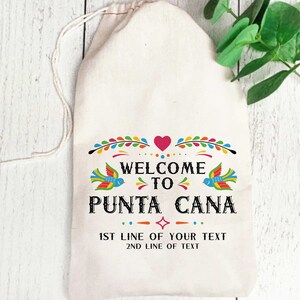 May include: A white cotton drawstring bag with a colorful design that says "Welcome to Punta Cana". The design includes birds, flowers, and a heart. The bag also has the text "1st line of your text" and "2nd line of text".