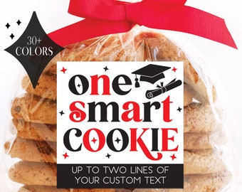 May include: A stack of round cookies in a clear plastic bag tied with a red ribbon. A white label features the black and red text "one smart COOKIE" with a graduation cap and diploma icon, plus "30+ COLORS" and "UP TO TWO LINES OF YOUR CUSTOM TEXT".