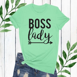 May include: A light green t-shirt with the text "BOSS lady" in black lettering and a black arrow pointing to the right.
