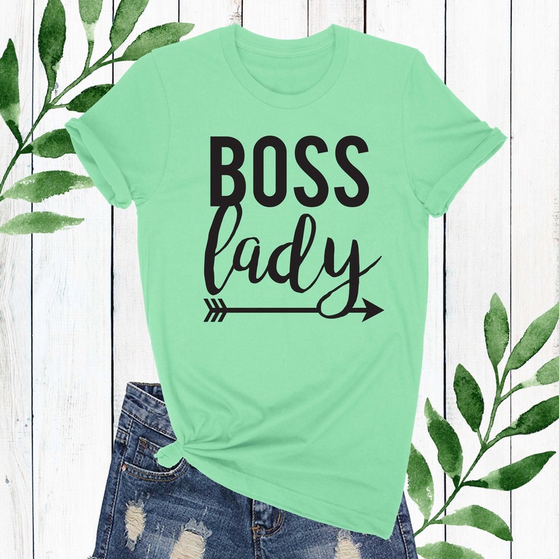 May include: A light green t-shirt with the text "BOSS lady" in black lettering and a black arrow pointing to the right.